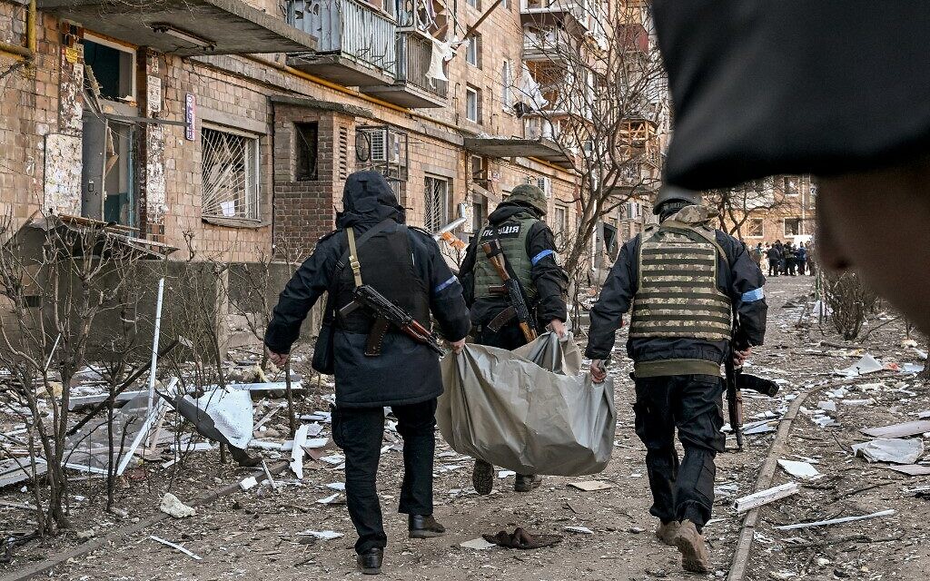 Ukrainian policemen carry a body away from a five-story residential building that partially collapsed after a shelling in Kyiv on March 18, 2022, as Russian troops try to encircle the Ukrainian capital as part of their slow-moving offensive (Sergei SUPINSKY / AFP)