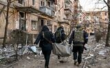 Ukrainian policemen carry a body away from a five-storey residential building that partially collapsed after a shelling in Kyiv on March 18, 2022 (Sergei SUPINSKY / AFP)