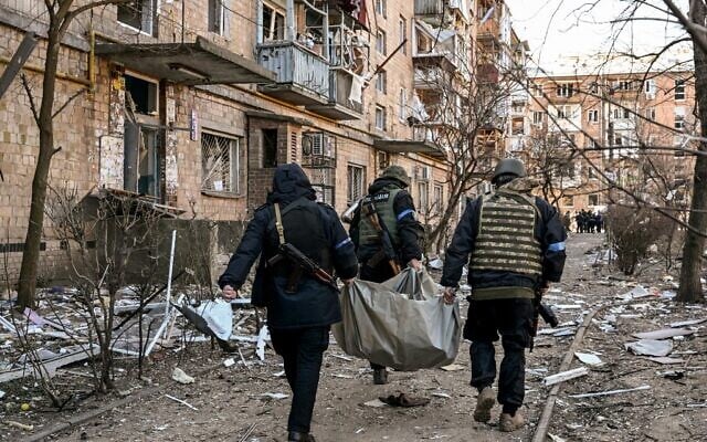 Ukrainian policemen carry a body away from a five-storey residential building that partially collapsed after a shelling in Kyiv on March 18, 2022 (Sergei SUPINSKY / AFP)