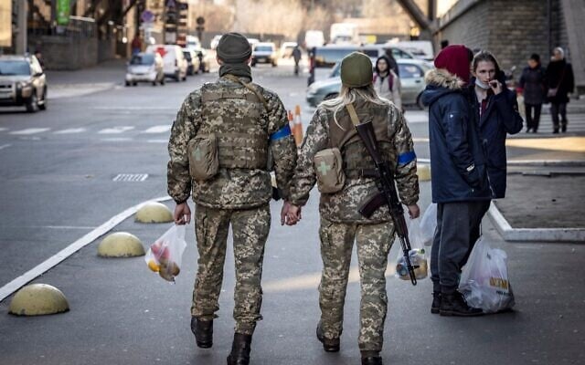 A couple of Ukrainian soldiers hold hands as they walk in the street in Kyiv, on March 18, 2022. (FADEL SENNA / AFP) A couple of Ukrainian soldiers hold hands as they walk in the street in Kyiv, on March 18, 2022. (FADEL SENNA / AFP)