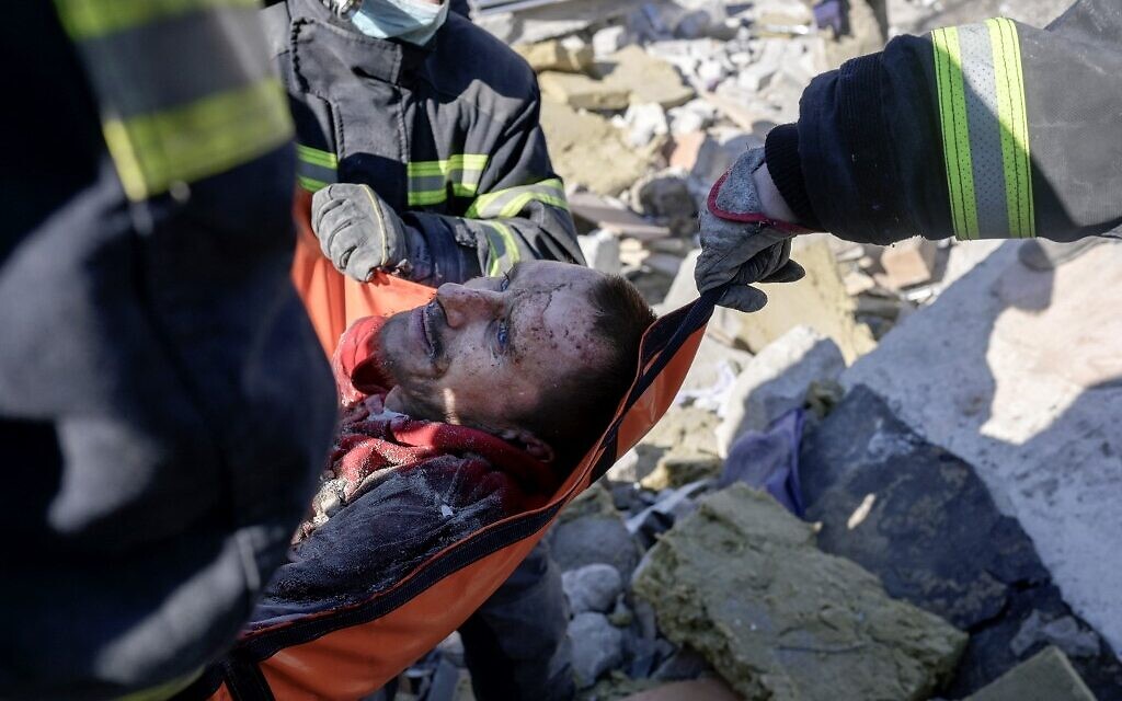 Rescuers carry a Ukrainian soldier saved after 30 hours from debris of the military school hit by Russian rockets, in Mykolaiv, southern Ukraine, on March 19, 2022. (BULENT KILIC / AFP)