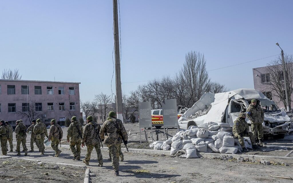 Ukrainian soldiers walk next to the military school hit by Russian rockets the day before, in Mykolaiv, southern Ukraine, on March 19, 2022. (BULENT KILIC / AFP)
