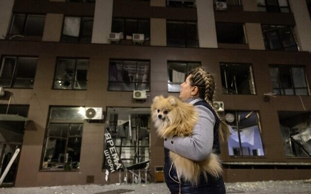 A resident, carrying her dog, leaves her apartment after a warehouse was hit by debris from a downed rocket in Kyiv on March 20, 2022. (FADEL SENNA / AFP)