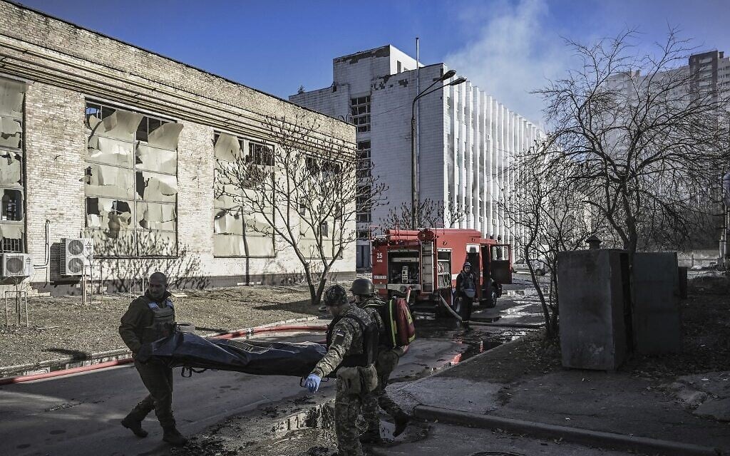 Military emergency service members remove the body of a dead Ukrainian serviceman in the area of a research institute, part of Ukraine's National Academy of Science, after a strike, in northwestern Kyiv, on March 22, 2022.(Aris Messinis / AFP)