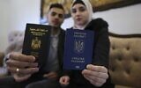 Ukrainian Viktoria Saidam (R), accompanied by her Palestinian husband Ibrahim Saidam, show their passports at their family home in the refugee camp of Bureij in the central Gaza Strip, March 22, 2022. (Photo by SAID KHATIB / AFP)