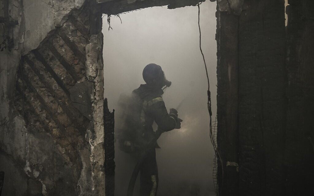 Firefighters extinguish a burning house hit by Russian Grad rockets in Kyiv's Shevchenkivsky district, on March 23, 2022. (Aris Messinis / AFP)