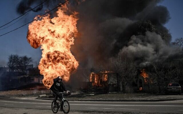 A cyclist rides past flames and smoke rising from a fire following an artillery fire on the 30th day of the invasion of Ukraine by Russian forces in the northeastern city of Kharkiv on March 25, 2022. (Aris Messinis / AFP) A cyclist rides past flames and smoke rising from a fire following an artillery fire on the 30th day of the invasion of Ukraine by Russian forces in the northeastern city of Kharkiv on March 25, 2022. (Aris Messinis / AFP)