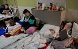 Children and parents pass the time in the basement of a hospital in Mykolaiv, March 26, 2022. (BULENT KILIC / AFP)