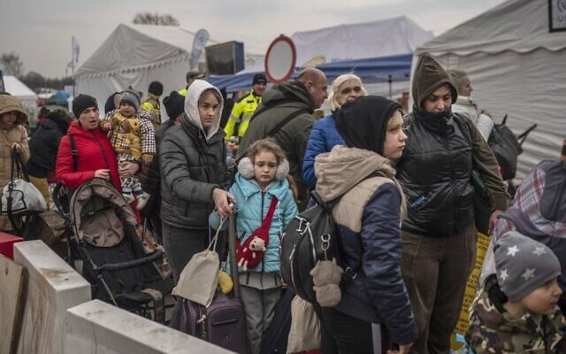 Ukrainian evacuees line up as they wait for further transport at the Medyka border crossing, after they crossed the Ukrainian-Polish border, southeastern Poland, on March 29, 2022. (Angelos Tzortzinis / AFP)