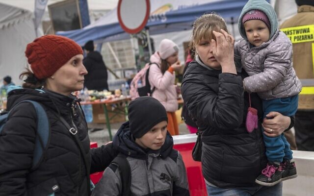 Ukrainian evacuees line up as they wait for further transport at the Medyka border crossing, after they crossed the Ukrainian-Polish border, southeastern Poland, on March 29, 2022. (Angelos Tzortzinis / AFP)