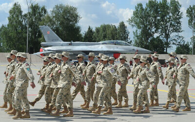 Polish Army soldiers march in front of a Polish Air Force F-16 fighter jet in Janow, Poland, July 4, 2016. (AP Photo/Alik Keplicz)