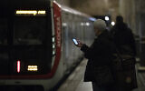 A man checks his smartphone while waiting to board a subway in Moscow, Russia, Dec. 23, 2019 (AP Photo/Pavel Golovkin)