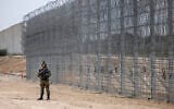 An Israeli soldier stands guard during a ceremony opening the newly completed underground barrier along the Israel-Gaza border, on December 7, 2021. (AP Photo/Tsafrir Abayov)