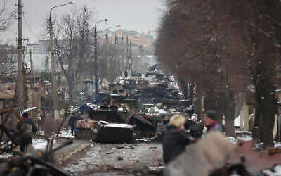 Illustrative: People look at the gutted remains of Russian military vehicles on a road in the town of Bucha, close to the capital Kyiv, Ukraine, Tuesday, March 1, 2022. (AP/Serhii Nuzhnenko)