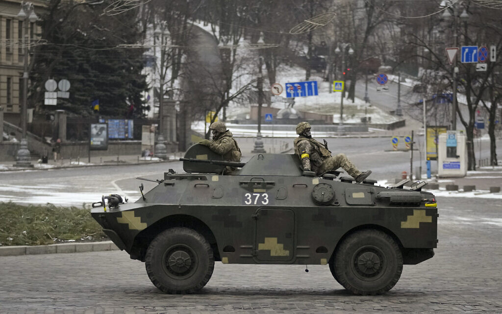 Ukrainian servicemen ride on top of an armored personnel carrier speeding down a deserted boulevard during an air raid alarm, in Kyiv, Ukraine, March 1, 2022. (AP Photo/Vadim Ghirda)