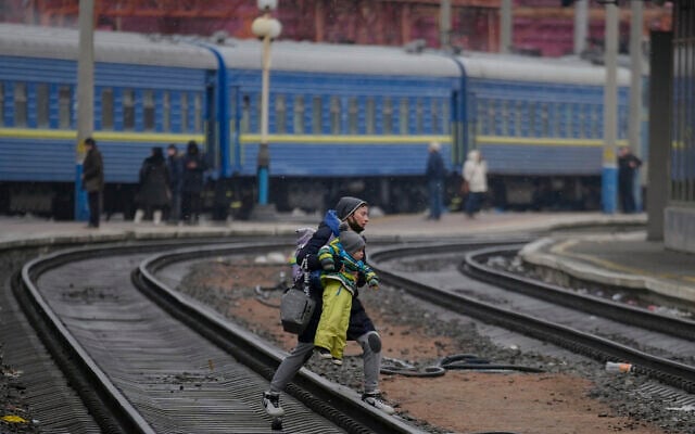 A woman carries a baby over the tracks trying to board a Lviv bound train, in Kyiv, Ukraine, on Thursday, March 3, 2022. (AP Photo/Vadim Ghirda) A woman carries a baby over the tracks trying to board a Lviv bound train, in Kyiv, Ukraine, on Thursday, March 3, 2022. (AP Photo/Vadim Ghirda)