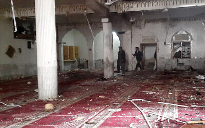 Volunteers examine the site of explosion inside a Shiite mosque in Peshawar, Pakistan, on Friday, March 4, 2022. A powerful bomb exploded inside a Shiite Muslim mosque in Pakistan's northwestern city of Peshawar on Friday, killing more than 30 worshippers and wounding dozens more, many of them critically, police said. (AP Photo/Muhammad Sajjad)