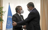 Head of Atomic Energy Organization of Iran Mohammad Eslami, right, and International Atomic Energy Agency director general Rafael Mariano Grossi shake hands at the start of their meeting in Tehran on March 5, 2022. (AP Photo/Vahid Salemi)