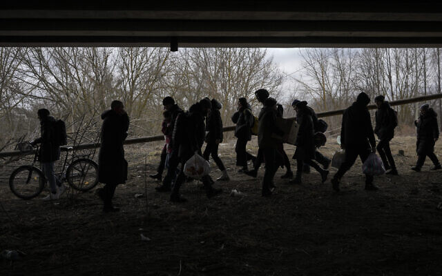 People cross on an improvised path under a bridge that was destroyed by a Russian airstrike, while fleeing the town of Irpin, Ukraine, March 5, 2022. (AP Photo/Vadim Ghirda) People cross on an improvised path under a bridge that was destroyed by a Russian airstrike, while fleeing the town of Irpin, Ukraine, March 5, 2022. (AP Photo/Vadim Ghirda)