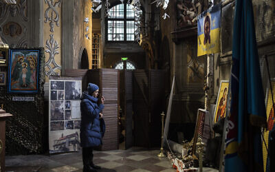 A Christian worshiper prays in front of a memorial to fallen soldiers at the Saints Peter and Paul Garrison Church in Lviv, western Ukraine, March 6, 2022. The memorial is dedicated to Ukrainian soldiers who died after 2014. (AP Photo/Bernat Armangue)