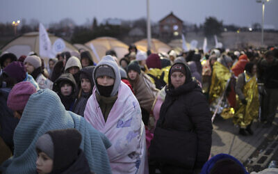 Refugees wait in a crowd for transportation after fleeing from Ukraine and arriving at the border crossing in Medyka, Poland, March 7, 2022. (AP Photo/Markus Schreiber)