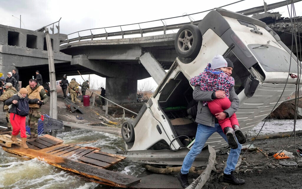 People cross an improvised path under a destroyed bridge while fleeing the town of Irpin close to Kyiv, Ukraine, March 7, 2022 (AP Photo/Efrem Lukatsky)