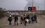 A Ukrainian police officer helps people as artillery echoes nearby while fleeing Irpin in the outskirts of Kyiv, Ukraine, March 7, 2022. (AP Photo/Emilio Morenatti)