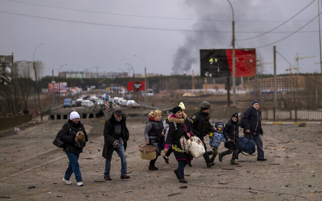A Ukrainian police officer helps people as artillery echoes nearby while fleeing Irpin in the outskirts of Kyiv, Ukraine, March 7, 2022. (AP Photo/Emilio Morenatti) A Ukrainian police officer helps people as artillery echoes nearby while fleeing Irpin in the outskirts of Kyiv, Ukraine, March 7, 2022. (AP Photo/Emilio Morenatti)