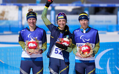 Ukraine's winners, gold medalist Iryna Bui, center, silver medalist Oleksandra Kononova, left, and bronze medalist Liudmyla Liashenko celebrate after the women's middle distance standing event at the 2022 Winter Paralympics, in Zhangjiakou, China, March 8, 2022. (Shuji Kajiama/AP)