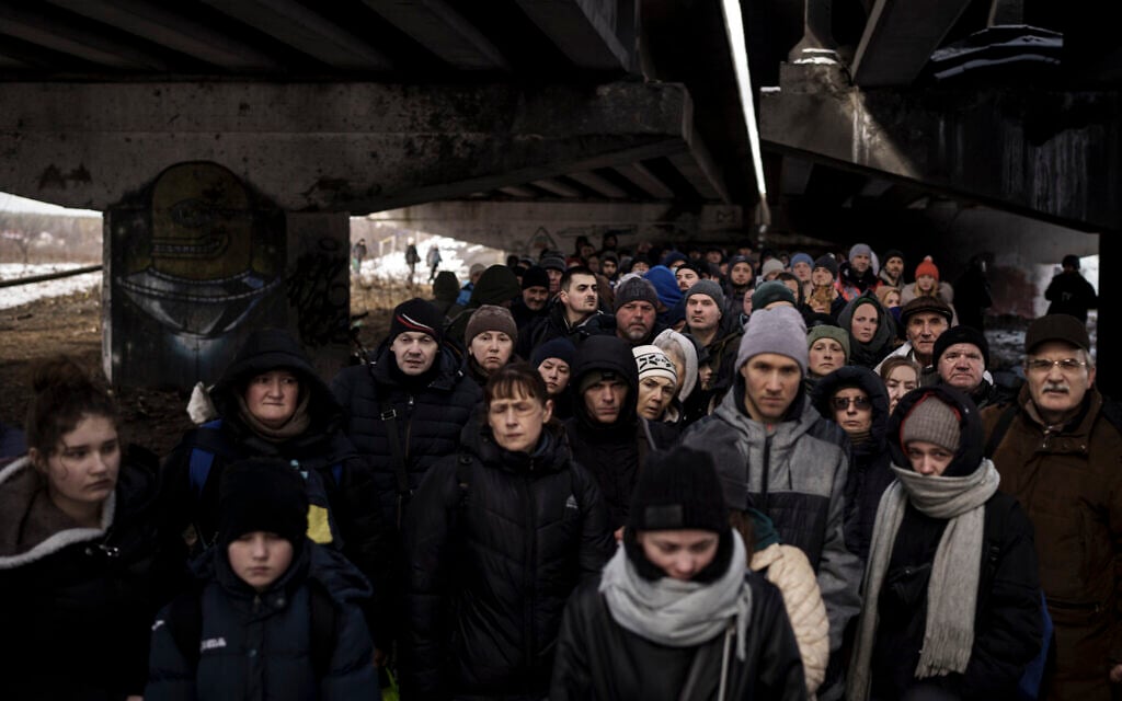 Ukrainians crowd under a destroyed bridge as they try to flee crossing the Irpin river in the outskirts of Kyiv, Ukraine, March 8, 2022. (AP Photo/Felipe Dana)