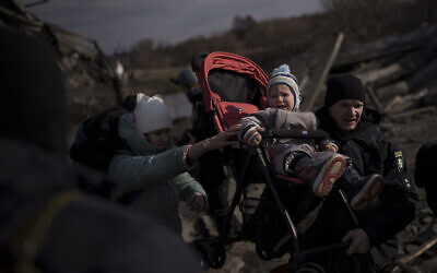 A child is carried on a stroller across an improvised path while fleeing Irpin, on the outskirts of Kyiv, Ukraine, March 9, 2022. (AP Photo/Felipe Dana)