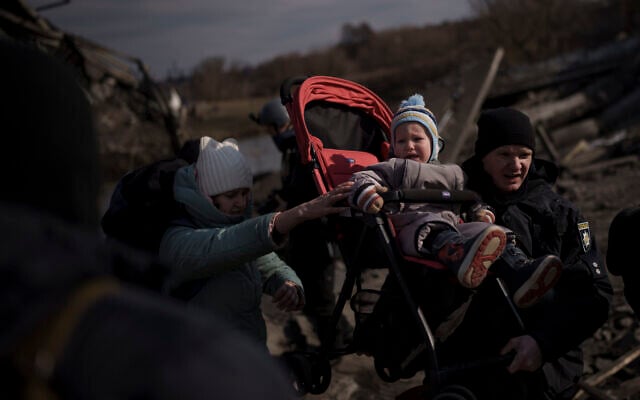 A child is carried on a stroller across an improvised path while fleeing Irpin, on the outskirts of Kyiv, Ukraine, March 9, 2022. (AP Photo/Felipe Dana)