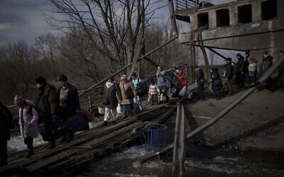 Ukrainians cross an improvised path under a destroyed bridge while fleeing Irpin, on the outskirts of Kyiv, Ukraine, on March 9, 2022. (AP Photo/Felipe Dana)