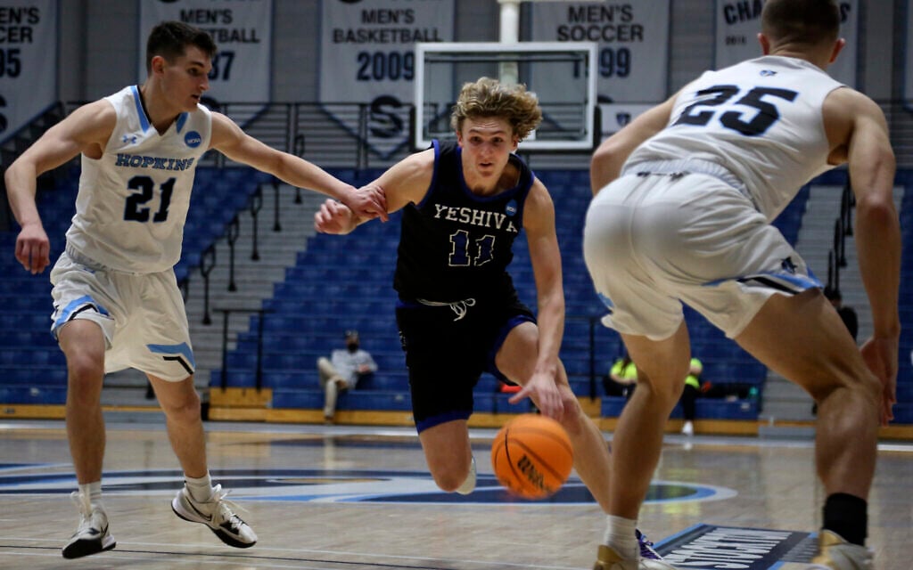 Yeshiva University's Ryan Turell (11) dribbles the ball down court while being defended by Johns Hopkins University's Carson James (21) and Lincoln Yeutter (25) in the first round of the NCAA's Division III basketball tournament, in Galloway Township, N.J., on Friday, March 4, 2022. The Yeshiva Maccabees lost to the Blue Jays, 63-59 at Stockton University Sports Center. (AP Photo/Jessie Wardarski)