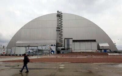 A man walks past a shelter covering the exploded reactor at the Chernobyl nuclear plant, in Chernobyl, Ukraine, April 15, 2021. (Efrem Lukatsky/AP)