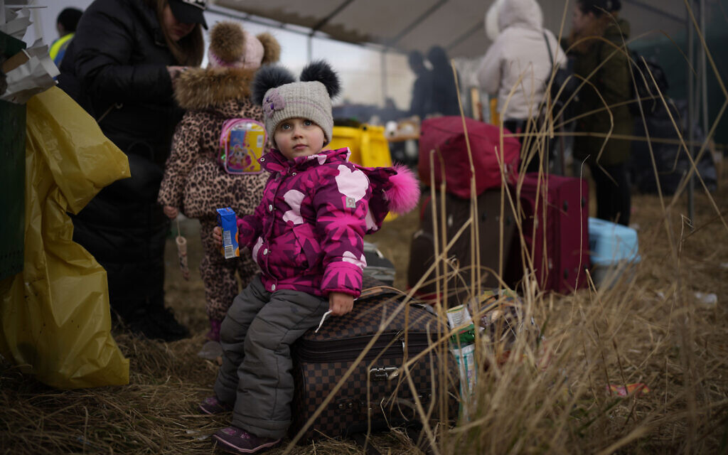A child sits on a suitcase as refugees fleeing war in neighboring Ukraine arrive at the Medyka border crossing, Poland, March 10, 2022. (AP Photo/Daniel Cole)
