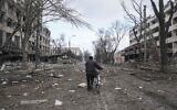 A man walks with a bicycle in a street damaged by shelling in Mariupol, Ukraine, Thursday, March 10, 2022. (AP Photo/Evgeniy Maloletka)