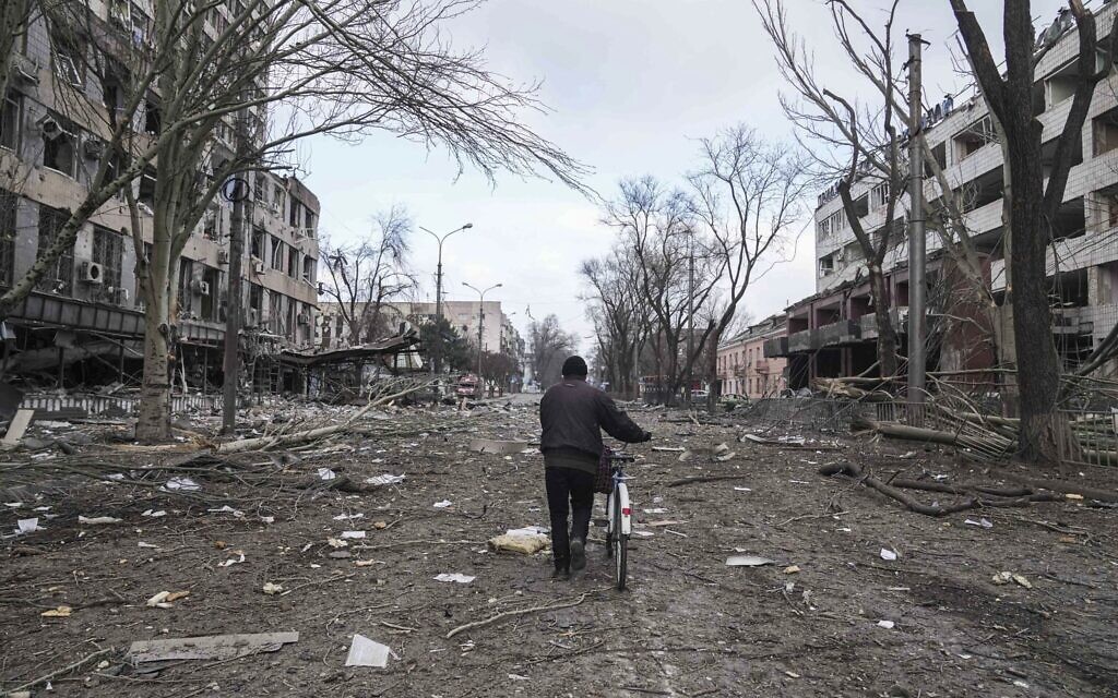 A man walks with a bicycle in a street damaged by shelling in Mariupol, Ukraine, on March 10, 2022. (AP Photo/Evgeniy Maloletka)