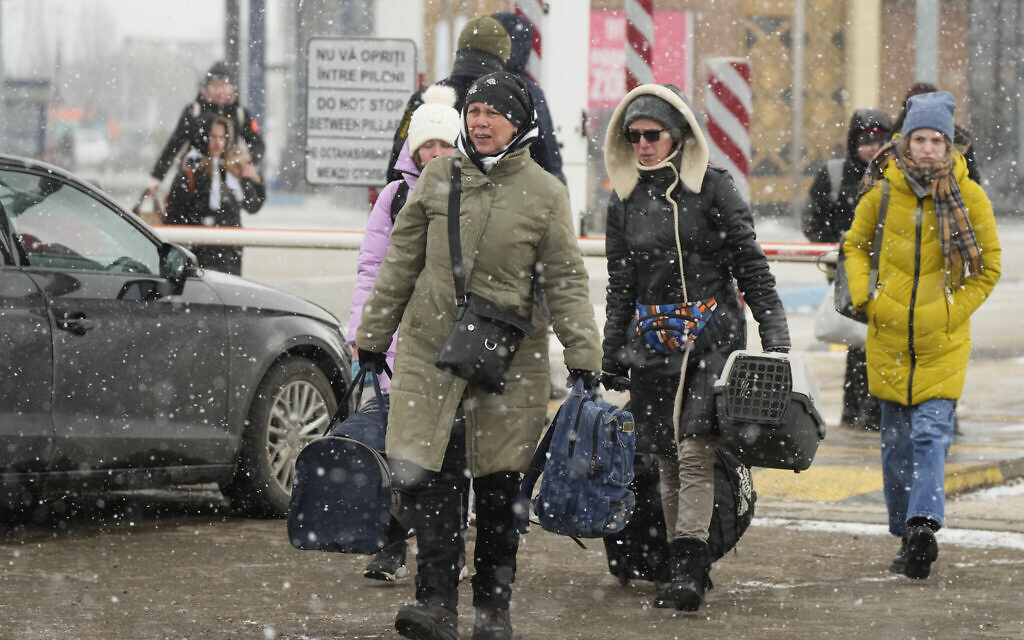 People carry their belongings after fleeing the war from neighboring Ukraine, at the border crossing in Palanca, Moldova, March 11, 2022. (AP Photo/Sergei Grits)