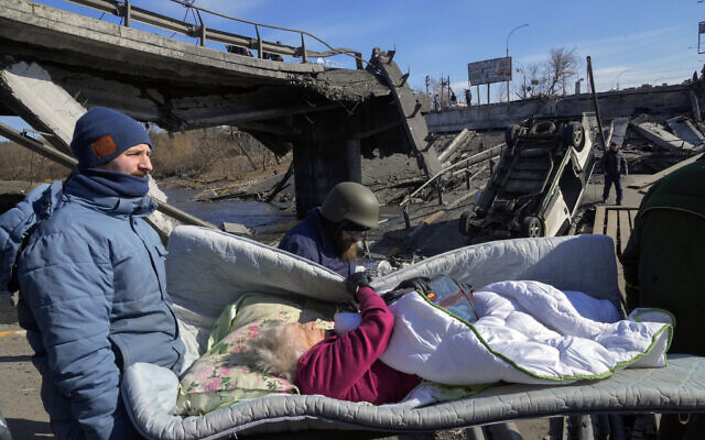 Volunteers pass an improvised path under a destroyed bridge as they evacuate an elderly resident in Irpin, some 25 kilometers (16 miles) northwest of Kyiv, Friday, on March 11, 2022. (AP/Efrem Lukatsky) Volunteers pass an improvised path under a destroyed bridge as they evacuate an elderly resident in Irpin, some 25 kilometers (16 miles) northwest of Kyiv, Friday, on March 11, 2022. (AP/Efrem Lukatsky)