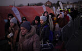 A group of people, who have fled Ukraine, stand in a line after arriving at the border crossing in Medyka, Poland, Sunday, March 13, 2022. (AP/Daniel Cole)