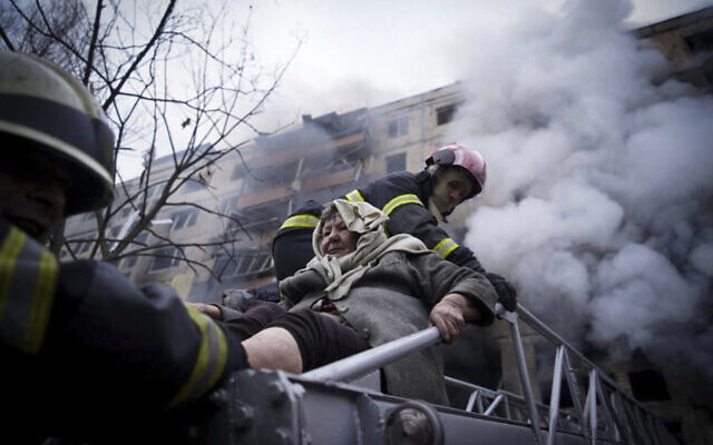 In this photo released by Ukrainian State Emergency Service press service, firefighters evacuate an elderly woman from an apartment building hit by shelling in Kyiv, Ukraine, March 14, 2022. (Ukrainian State Emergency Service via AP) In this photo released by Ukrainian State Emergency Service press service, firefighters evacuate an elderly woman from an apartment building hit by shelling in Kyiv, Ukraine, March 14, 2022. (Ukrainian State Emergency Service via AP)