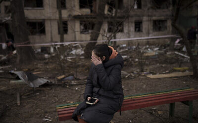 A resident sits outside a destroyed building after it was hit by artillery shelling in Kyiv, Ukraine, Monday, March 14, 2022. (AP Photo/Felipe Dana)