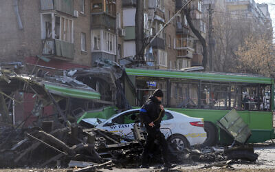 A Ukrainian soldier passes by a destroyed trolleybus and taxi after a Russian bombing attack in Kyiv, Ukraine, March 14, 2022. (Efrem Lukatsky/AP)