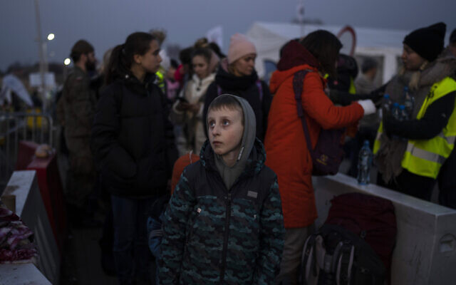 A boy stands with a group of people fleeing Ukraine as they stand in a line after arriving at the border crossing in Medyka, Poland, on Monday, March 14, 2022. (AP Photo/Petros Giannakouris) A boy stands with a group of people fleeing Ukraine as they stand in a line after arriving at the border crossing in Medyka, Poland, on Monday, March 14, 2022. (AP Photo/Petros Giannakouris)