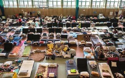 People who fled the war in Ukraine rest inside an indoor sports stadium being used as a refugee center, in the village of Medyka, a border crossing between Poland and Ukraine, on March 15, 2022.(AP Photo/Petros Giannakouris)