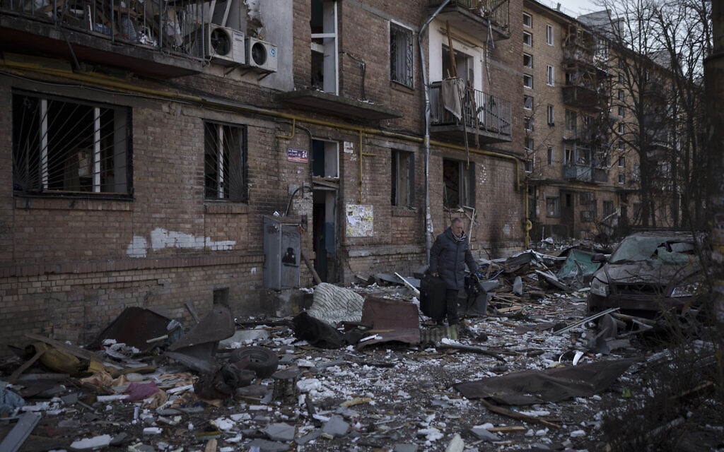 A resident carries a suitcase with his belongings after his building was heavily damaged by bombing in Kyiv, Ukraine, March 18, 2022 (AP Photo/Felipe Dana)