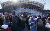 Hundreds of refugees from Ukraine wait in line to apply for Polish ID numbers that will entitle them to work, free health care and education, as well as family bonuses, at a special application point at the National Stadium in Warsaw, Poland, on March 19, 2022. (Czarek Sokolowski/AP)