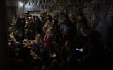 People gather in a basement, used as a bomb shelter, during an air raid in Lviv, Western Ukraine, Saturday, March 19, 2022. Lviv has been a refuge since the war began nearly a month ago, the last outpost before Poland and host to hundreds of thousands of Ukrainians streaming through or staying on. (AP Photo/Bernat Armangue)