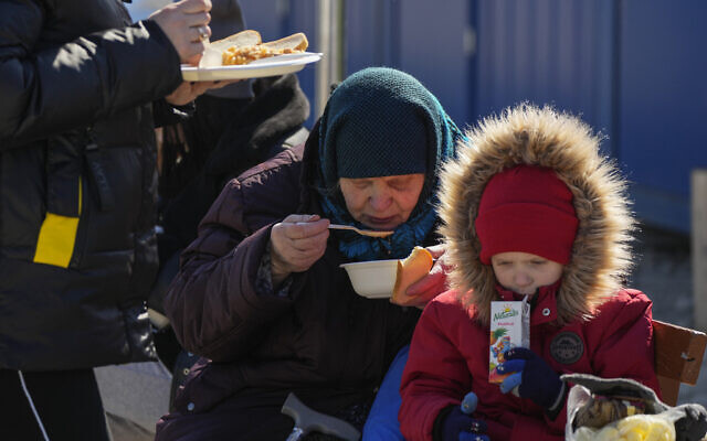 A refugee from the Ukrainian city of Mykolaiv, Ekaterina Mosha, 82, has a meal with her grandson Dmitrii, 3, after fleeing the war from neighboring Ukraine, at the border crossing in Palanca, Moldova, on March 19, 2022. (AP Photo/Sergei Grits) A refugee from the Ukrainian city of Mykolaiv, Ekaterina Mosha, 82, has a meal with her grandson Dmitrii, 3, after fleeing the war from neighboring Ukraine, at the border crossing in Palanca, Moldova, on March 19, 2022. (AP Photo/Sergei Grits)